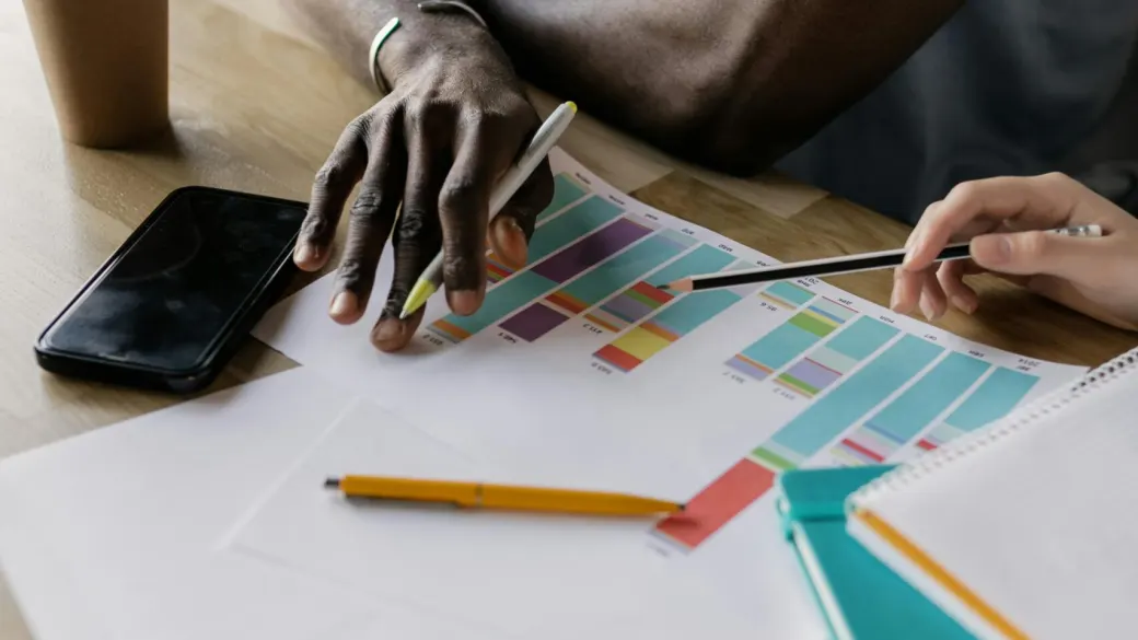 Hands mark up colour-coded planning sheets with a pencil.
