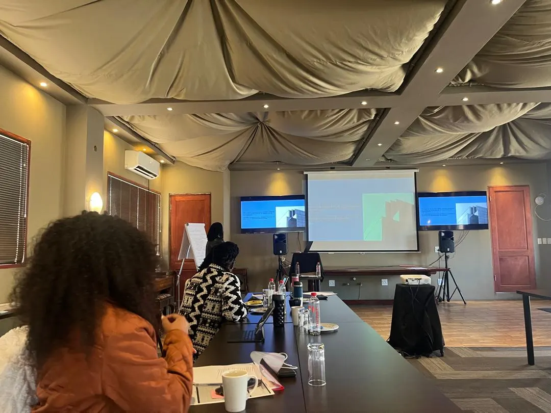 A participant follows a facilitated session, with the presentation on screens at the front of the room.